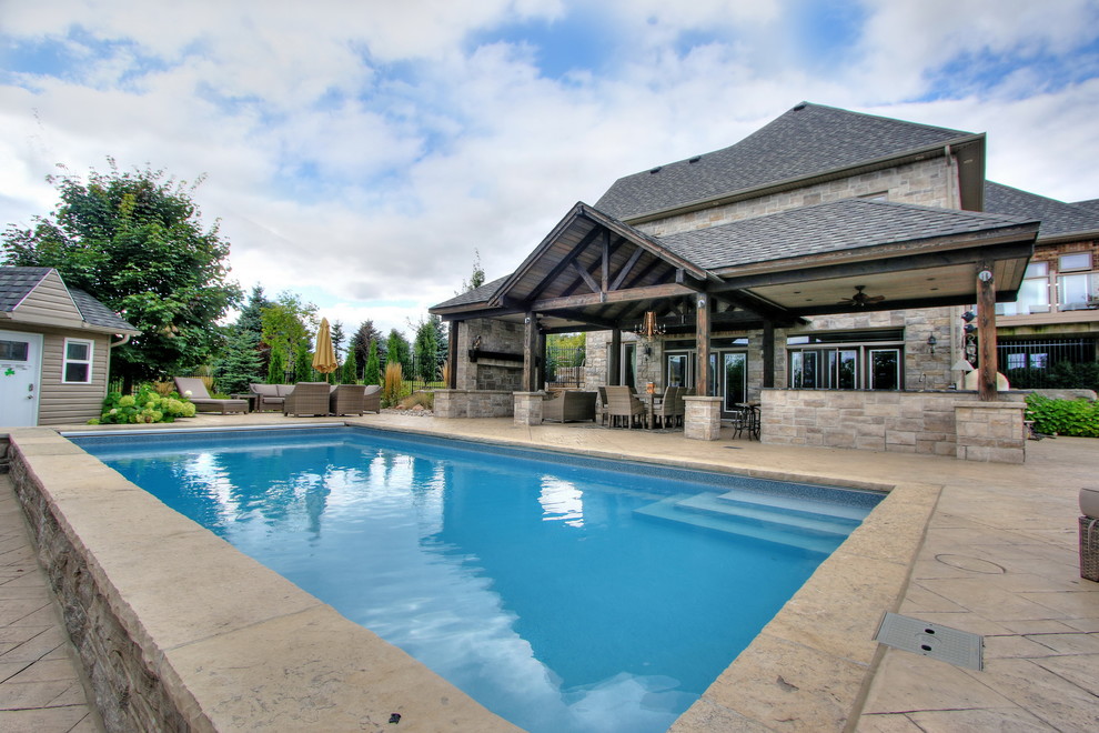 Esempio di una piscina chic rettangolare di medie dimensioni e dietro casa con una dépendance a bordo piscina e cemento stampato