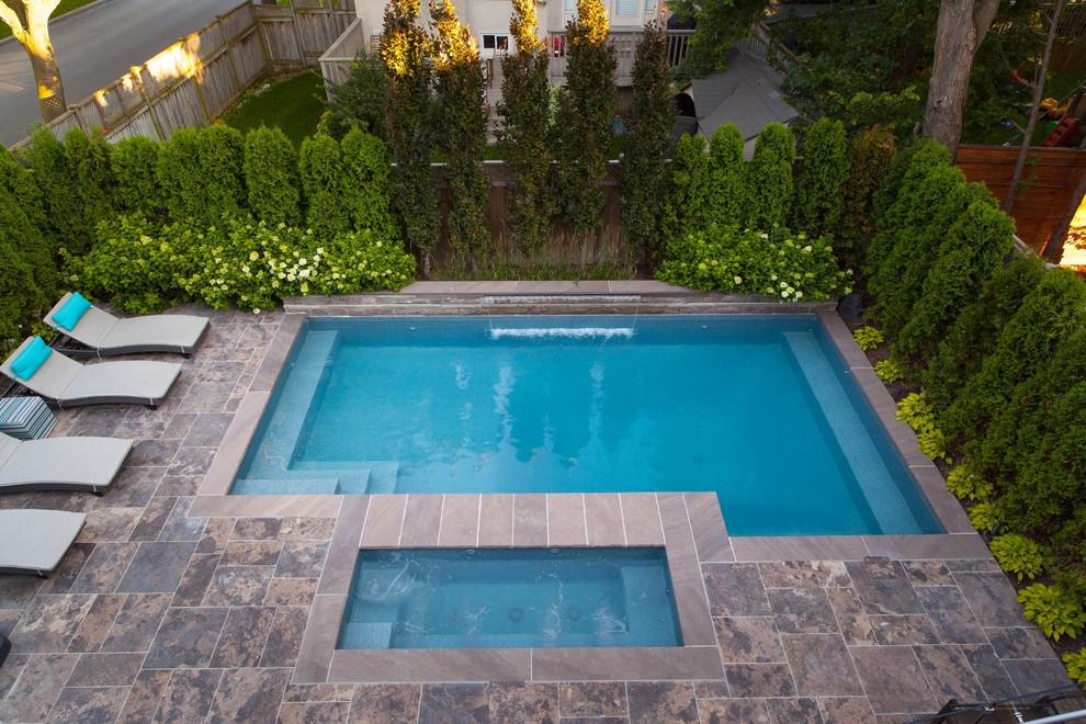 Modelo de piscinas y jacuzzis clásicos renovados pequeños rectangulares en patio trasero con adoquines de piedra natural