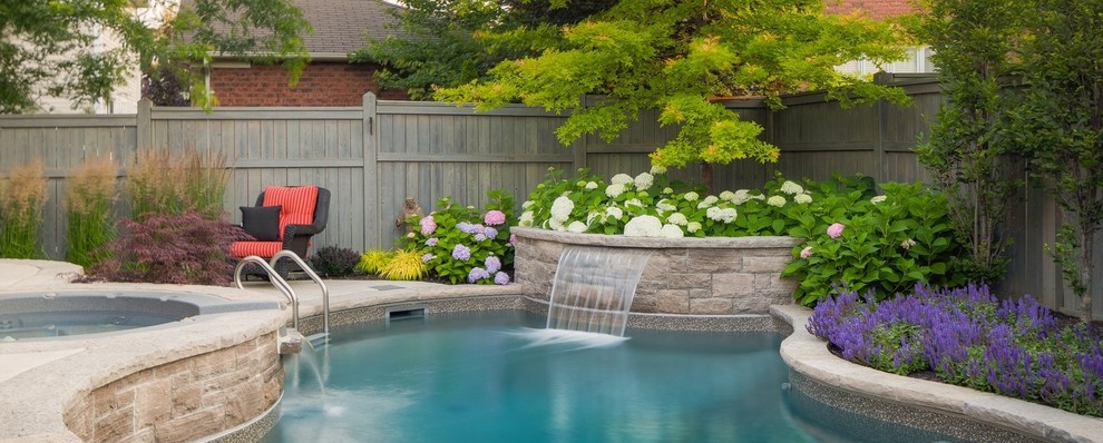 Immagine di una piccola piscina design dietro casa con fontane e cemento stampato