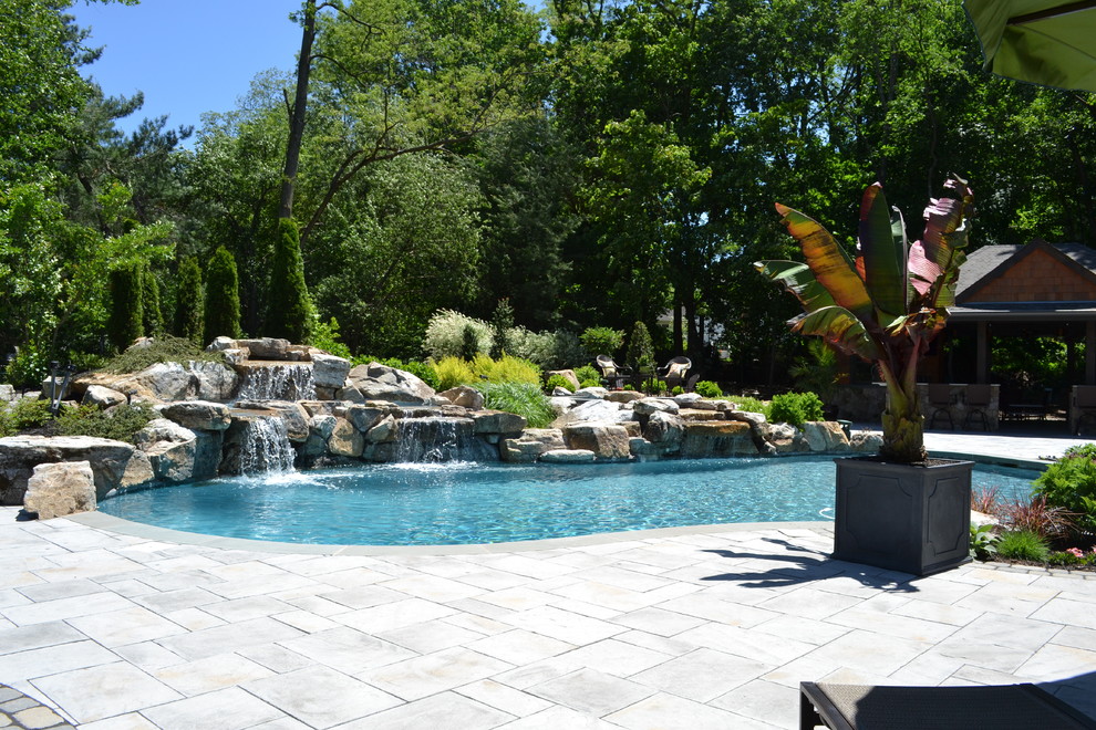 Foto di una grande piscina moderna personalizzata dietro casa con fontane e pavimentazioni in cemento