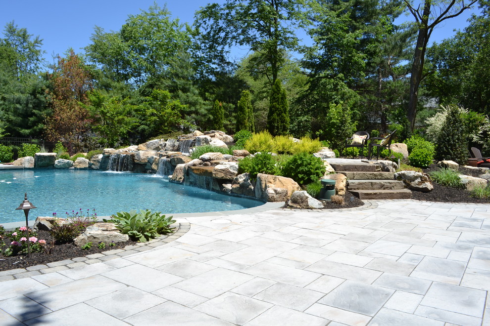 Immagine di una grande piscina minimalista personalizzata dietro casa con fontane e pavimentazioni in cemento