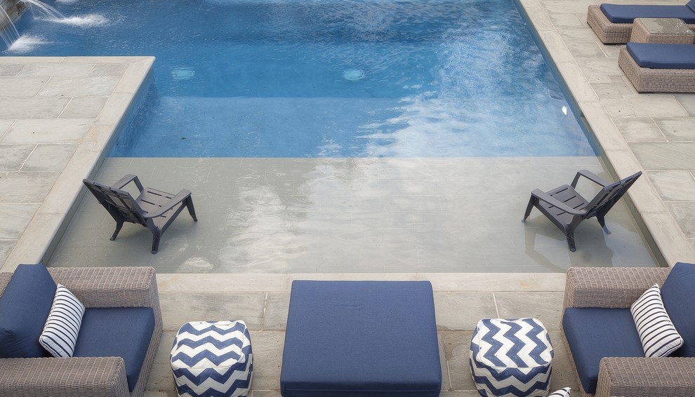 Diseño de piscina con tobogán alargada actual grande rectangular en patio lateral con adoquines de piedra natural