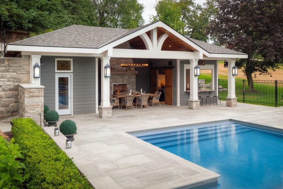 Large contemporary rectangular lengths swimming pool in Toronto with a pool house and natural stone paving.