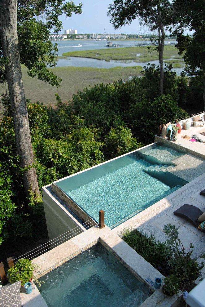 Immagine di una piscina a sfioro infinito stile marino rettangolare dietro casa con piastrelle