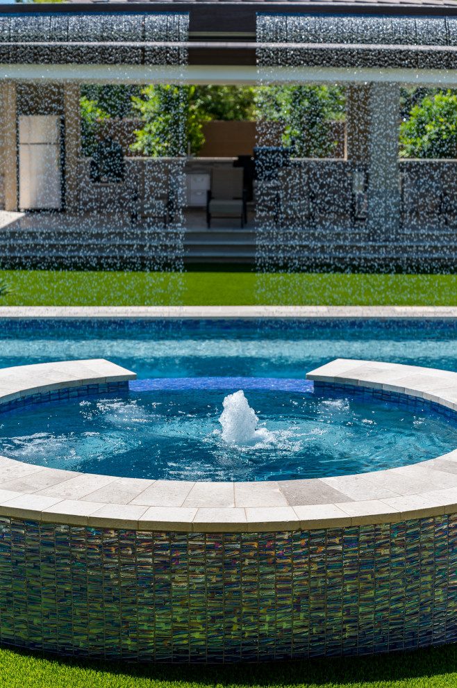 Idée de décoration pour une grande piscine arrière design rectangle avec un bain bouillonnant.