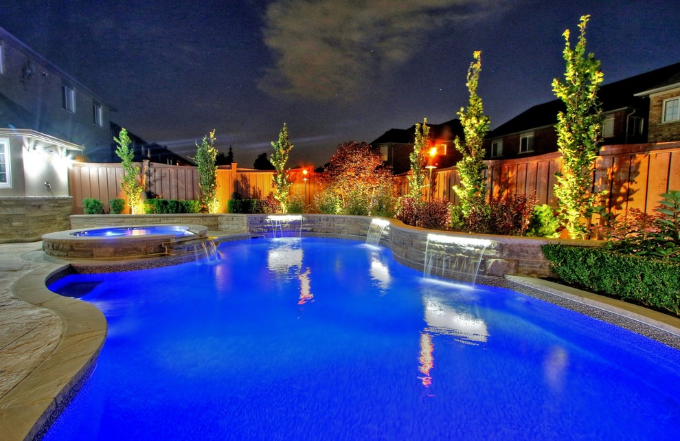 На фото: бассейн среднего размера, в форме фасоли на заднем дворе в стиле неоклассика (современная классика) с джакузи и покрытием из декоративного бетона