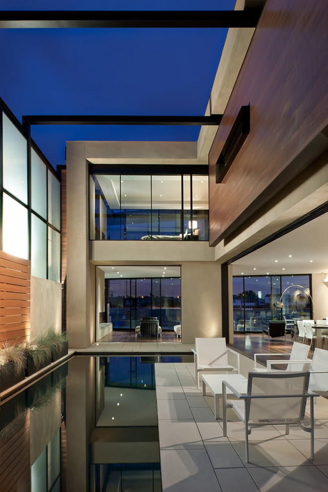 This is an example of a medium sized modern indoor l-shaped swimming pool in Los Angeles with concrete paving.