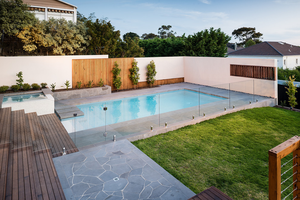 Aménagement d'une grande piscine moderne rectangle avec une terrasse en bois.