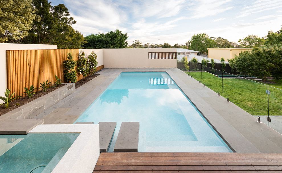 Стильный дизайн: огромный прямоугольный бассейн на заднем дворе в стиле модернизм с покрытием из каменной брусчатки - последний тренд