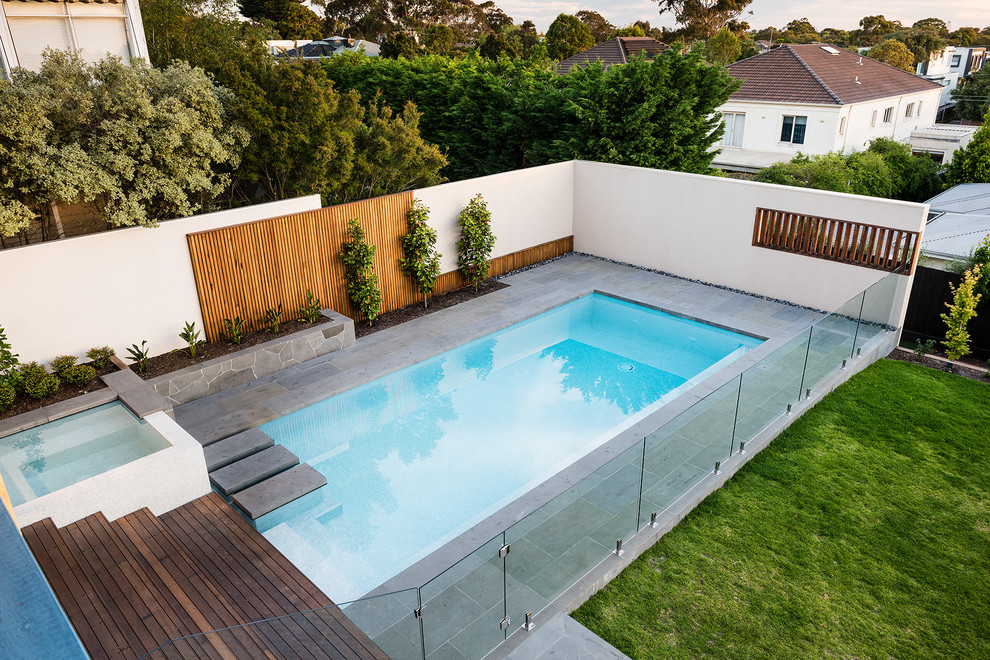 Exemple d'une grande piscine arrière moderne rectangle avec une terrasse en bois.