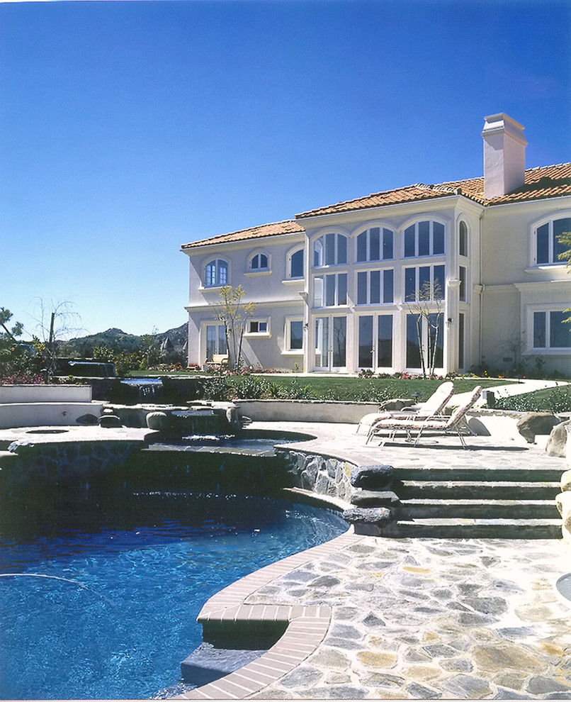 Ispirazione per una piscina naturale mediterranea personalizzata di medie dimensioni e dietro casa con una vasca idromassaggio e pavimentazioni in pietra naturale