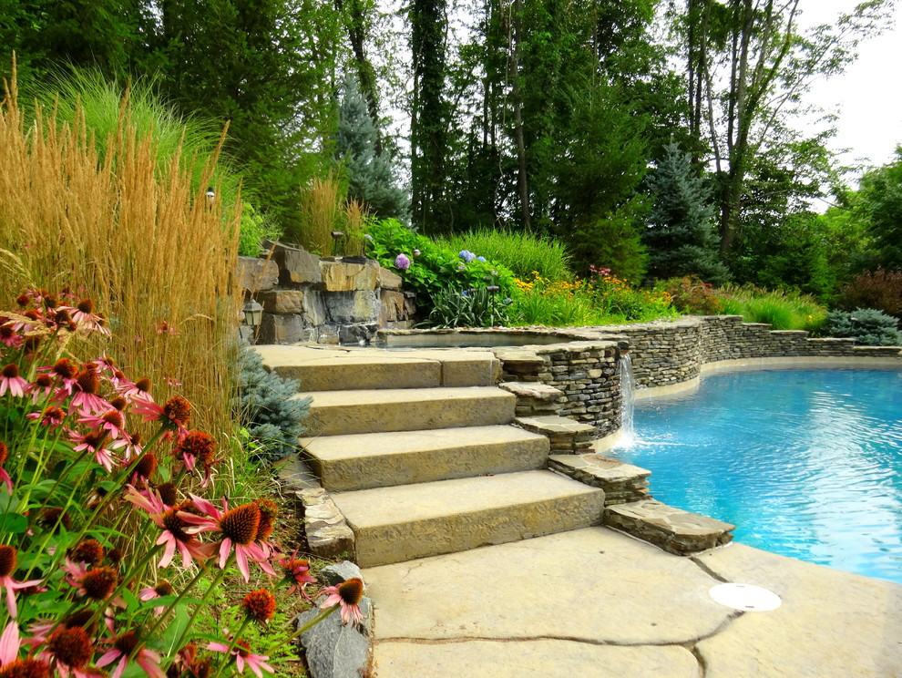 Ispirazione per una grande piscina naturale chic personalizzata dietro casa con una vasca idromassaggio e pavimentazioni in pietra naturale