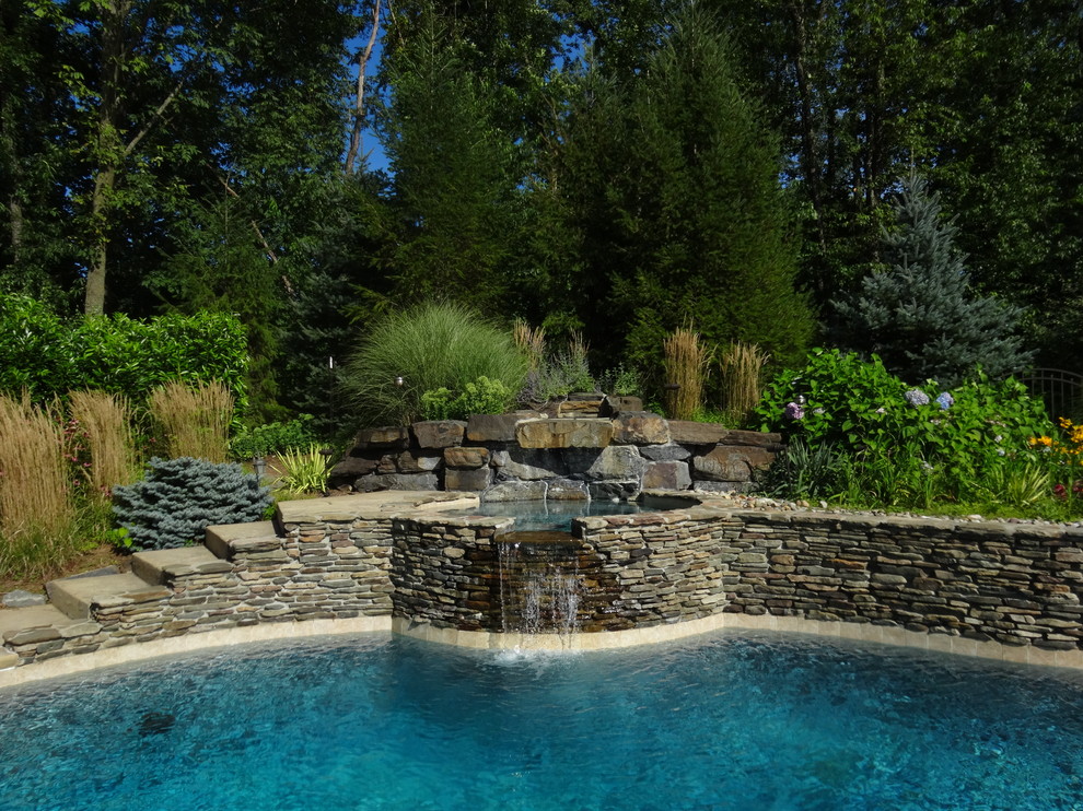 Large classic back custom shaped natural hot tub in New York with natural stone paving.