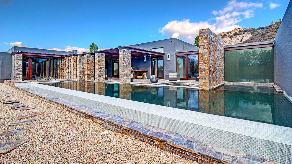 Hot tub - huge modern backyard gravel and rectangular infinity hot tub idea in Los Angeles