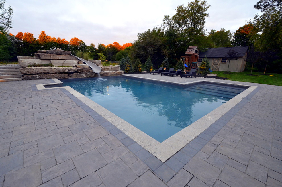 Photo of a contemporary back swimming pool in Toronto with a water slide and concrete paving.