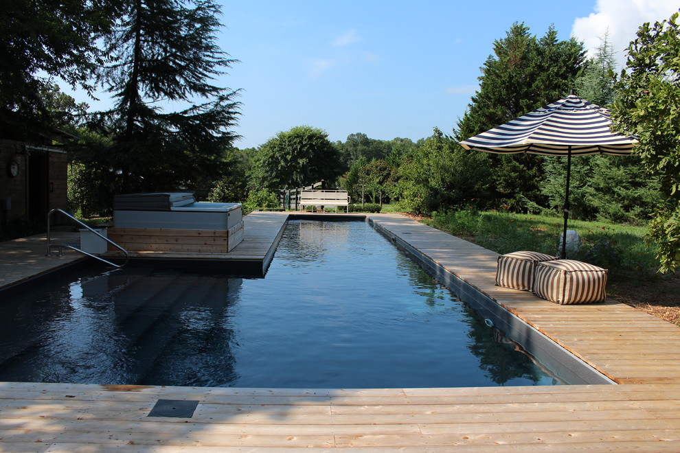 Aménagement d'une grande piscine naturelle et arrière montagne en L avec un bain bouillonnant et une terrasse en bois.