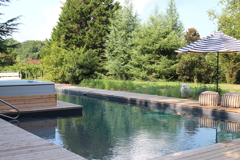 Idee per una grande piscina naturale rustica a "L" dietro casa con una vasca idromassaggio e pedane