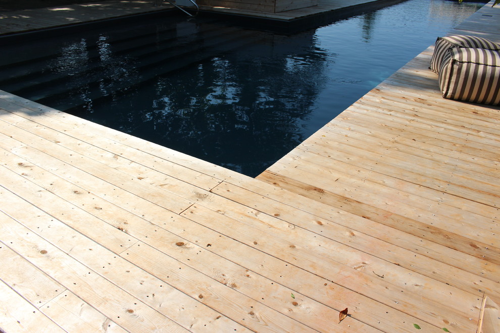 Cette image montre une grande piscine naturelle et arrière chalet en L avec un bain bouillonnant et une terrasse en bois.