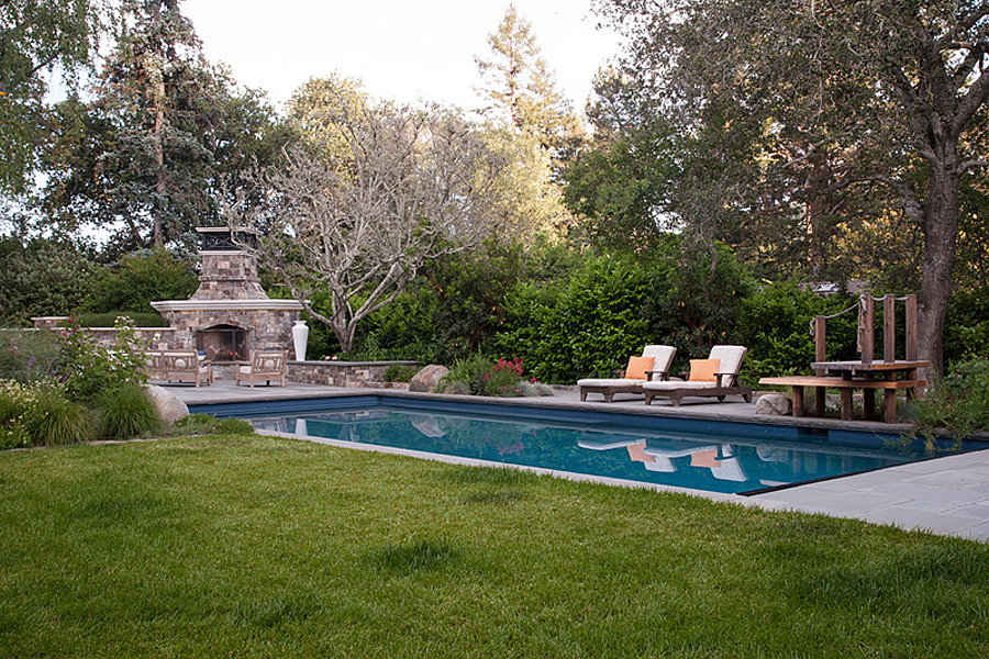 Modelo de piscina alargada clásica grande rectangular en patio lateral con adoquines de piedra natural