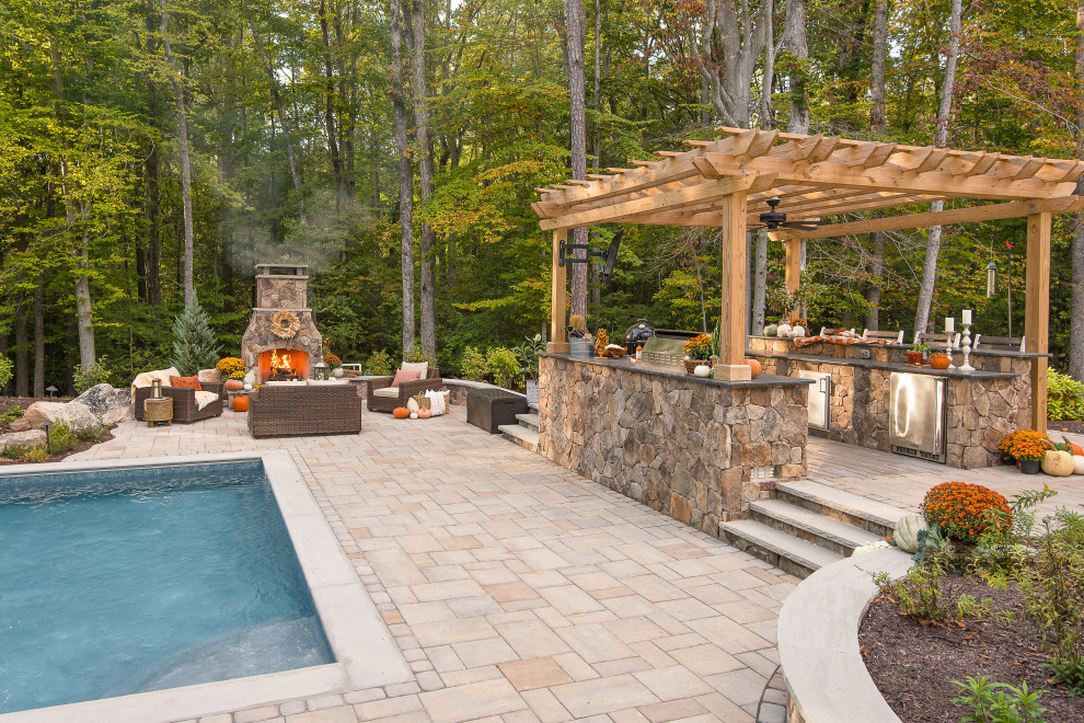 Ejemplo de piscina con fuente tradicional grande rectangular en patio trasero con adoquines de hormigón