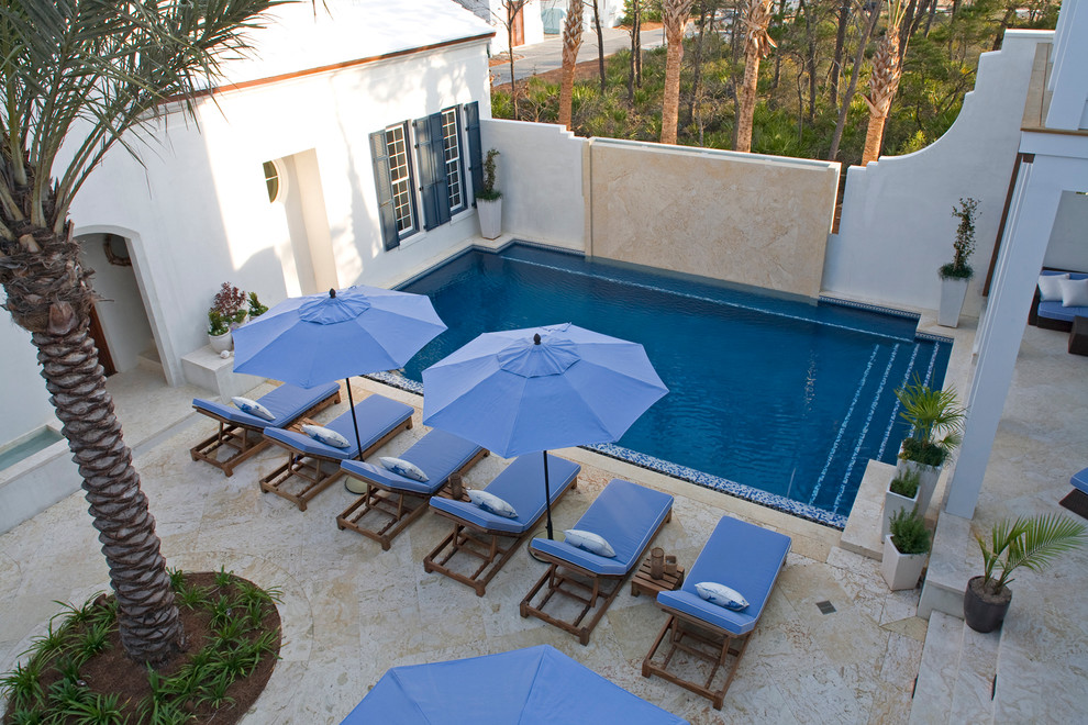 Cette image montre une piscine méditerranéenne de taille moyenne et rectangle avec un point d'eau, une cour et des pavés en pierre naturelle.