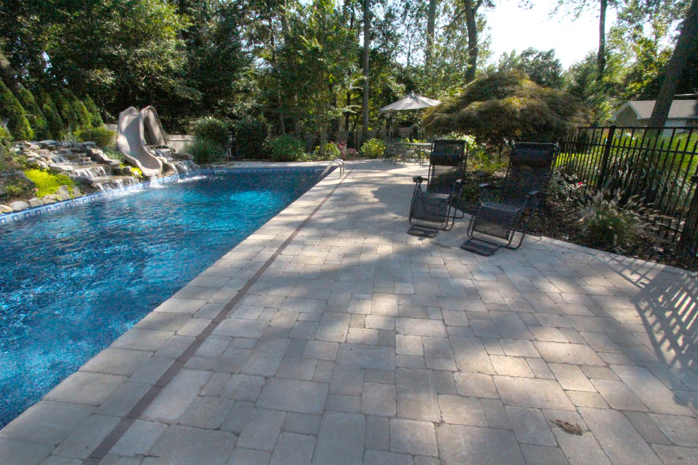 Modelo de piscina clásica rectangular en patio trasero con adoquines de hormigón