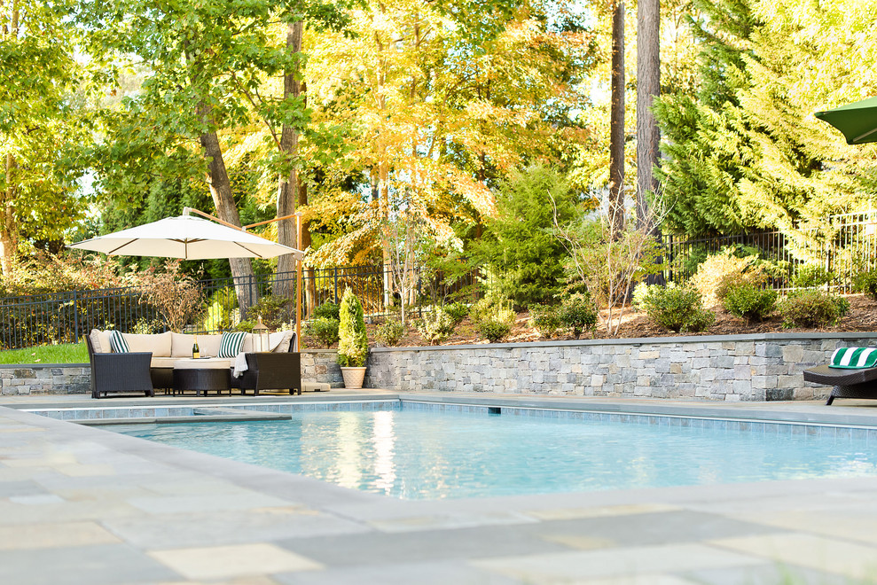 Esempio di una piscina tradizionale rettangolare di medie dimensioni e dietro casa con una vasca idromassaggio e pavimentazioni in pietra naturale