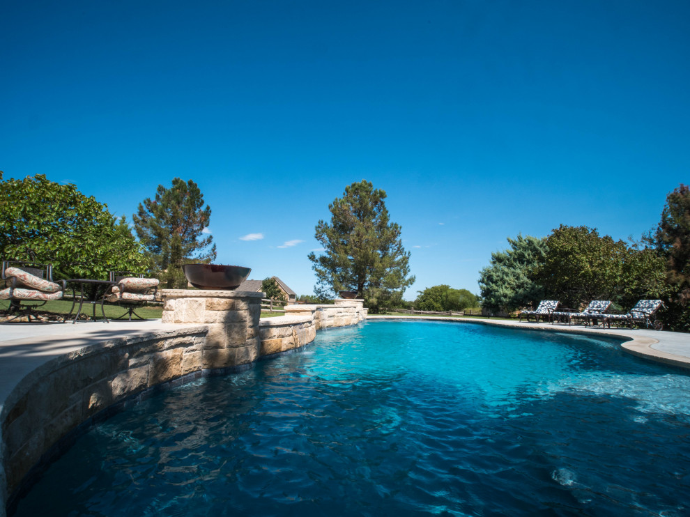 Ejemplo de piscina natural de estilo americano extra grande a medida en patio trasero con paisajismo de piscina y adoquines de hormigón