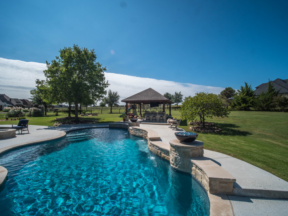 Diseño de piscina natural de estilo americano extra grande a medida en patio trasero con paisajismo de piscina y adoquines de hormigón