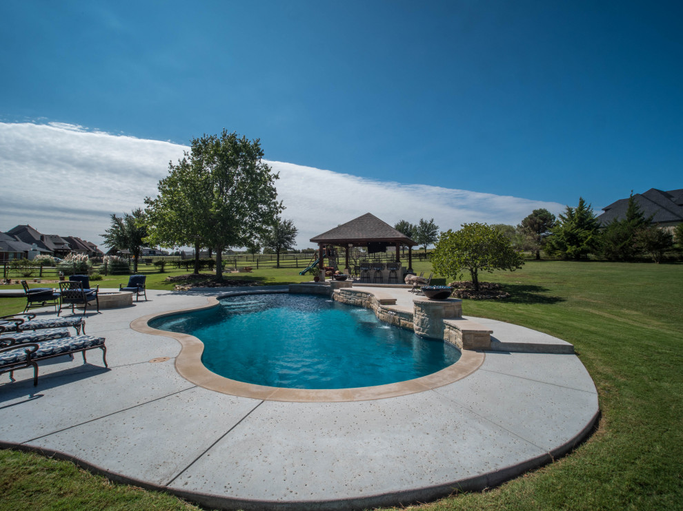 Imagen de piscina natural de estilo americano extra grande a medida en patio trasero con paisajismo de piscina y adoquines de hormigón