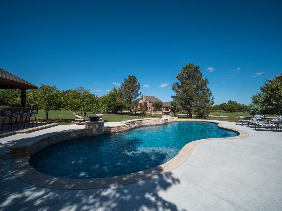 Modelo de piscina natural de estilo americano extra grande a medida en patio trasero con paisajismo de piscina y adoquines de hormigón
