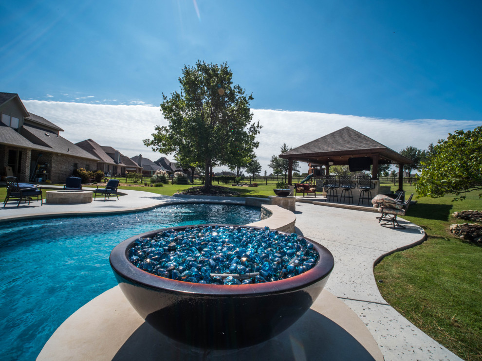 Ejemplo de piscina natural de estilo americano extra grande a medida en patio trasero con paisajismo de piscina y adoquines de hormigón