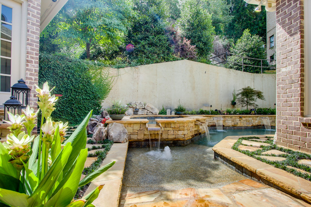 Esempio di una piscina monocorsia minimalista rettangolare di medie dimensioni e dietro casa con una vasca idromassaggio e pavimentazioni in pietra naturale