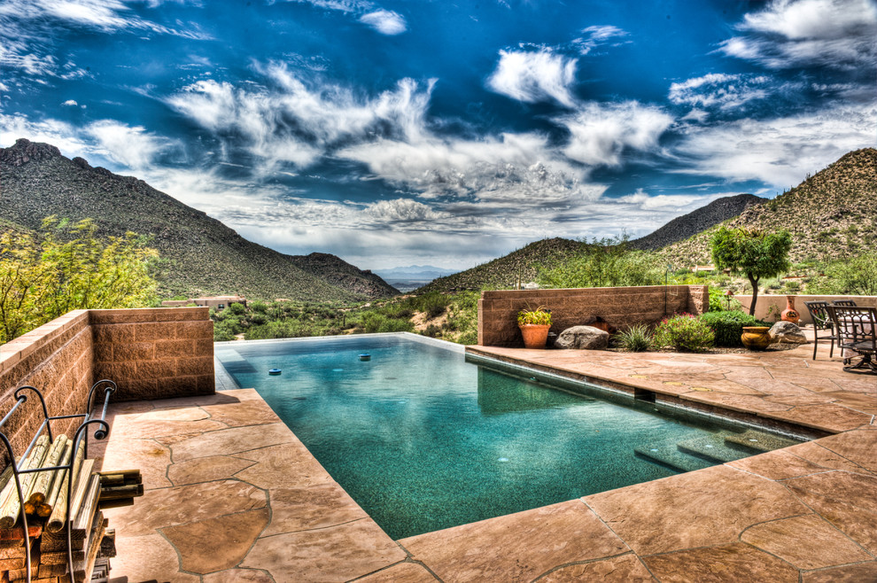 Immagine di una piscina a sfioro infinito american style rettangolare di medie dimensioni e dietro casa con una vasca idromassaggio e pavimentazioni in pietra naturale