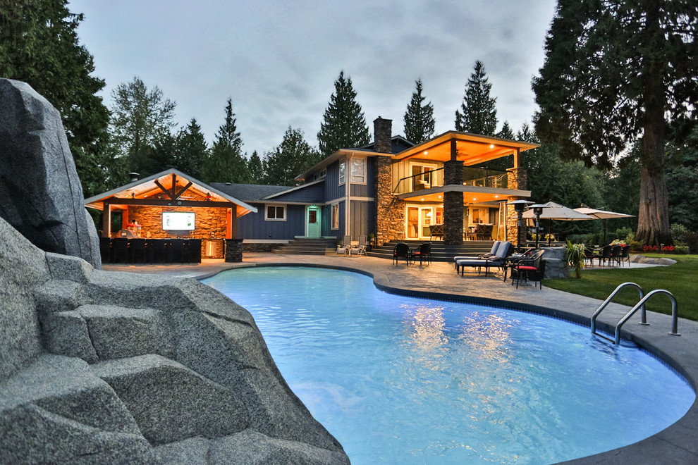 Diseño de piscina con tobogán natural de estilo americano extra grande a medida en patio trasero con suelo de hormigón estampado