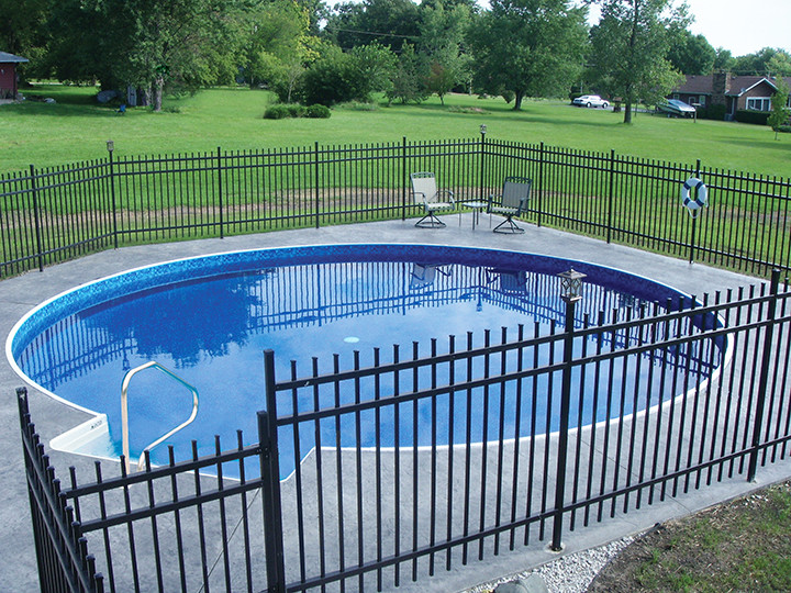 Ispirazione per una grande piscina tradizionale rotonda dietro casa con lastre di cemento
