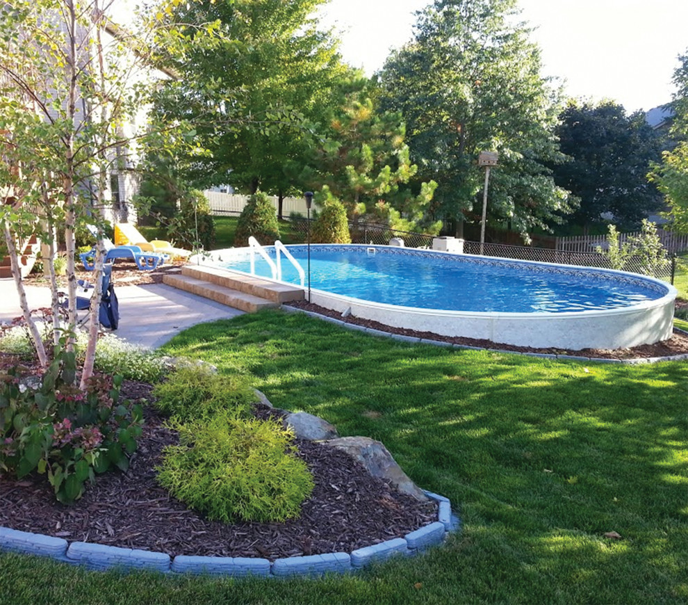 Imagen de piscina elevada actual de tamaño medio redondeada en patio trasero con losas de hormigón