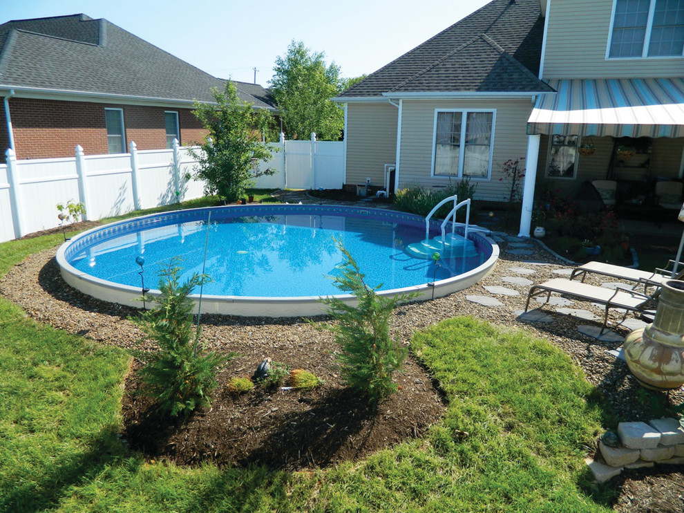 Modelo de piscina actual de tamaño medio redondeada en patio trasero con gravilla