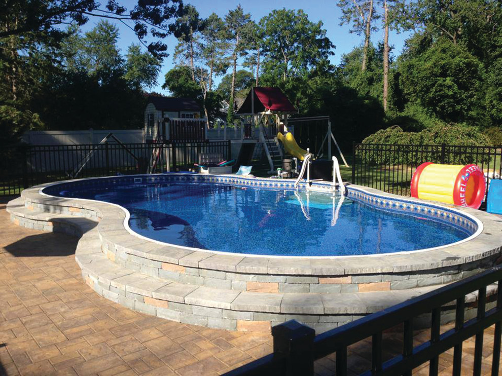 Foto de piscina alargada contemporánea de tamaño medio tipo riñón en patio trasero con adoquines de hormigón