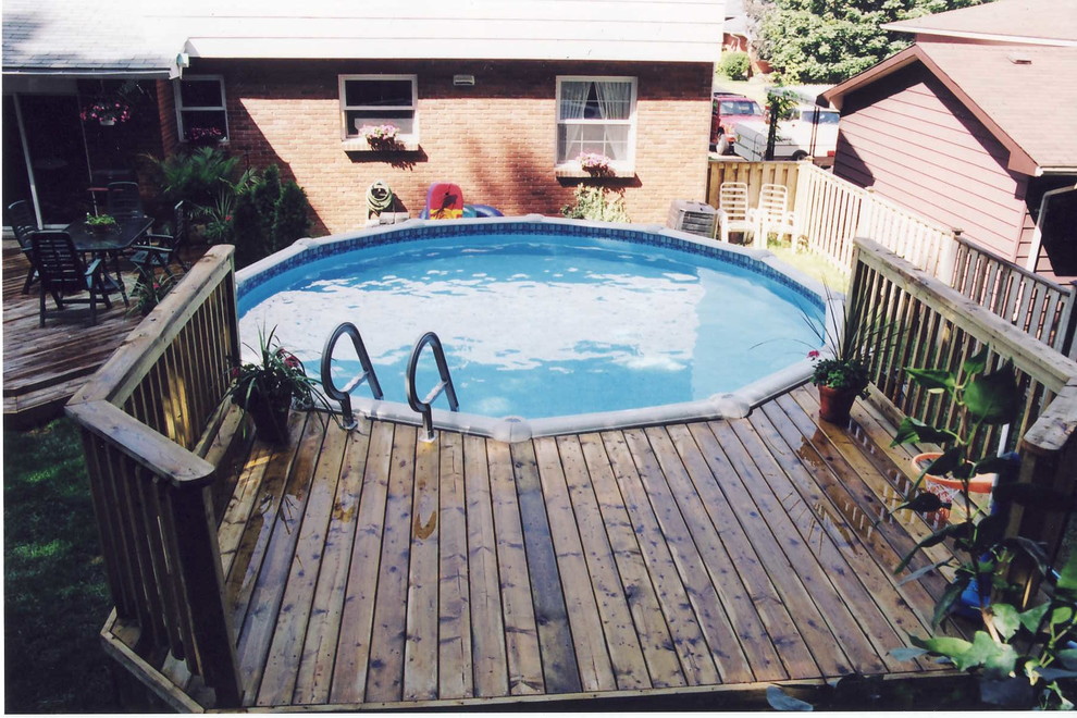Foto de piscina elevada clásica de tamaño medio redondeada en patio trasero con entablado
