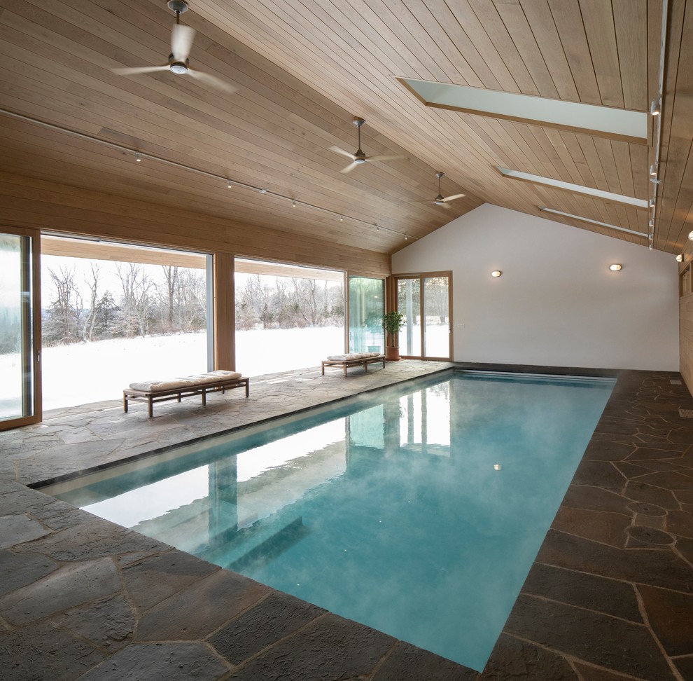 Réalisation d'une piscine design rectangle avec des pavés en pierre naturelle.