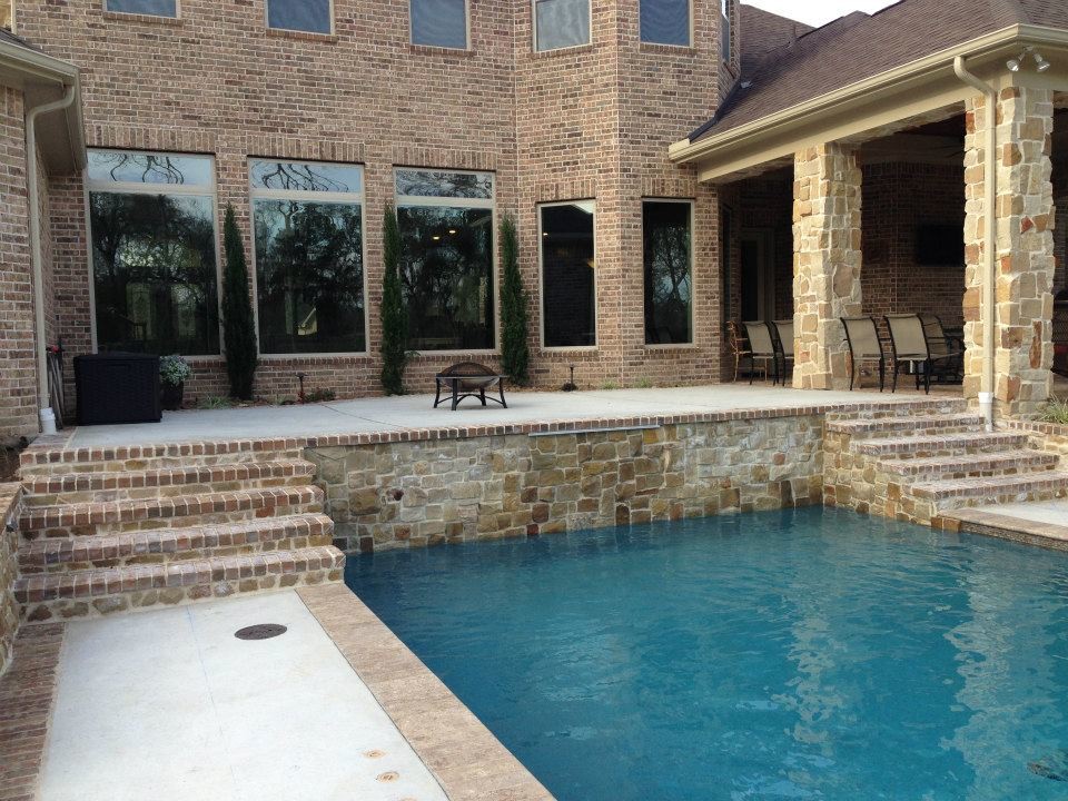 Imagen de piscina con fuente alargada de estilo americano de tamaño medio rectangular en patio trasero con adoquines de ladrillo