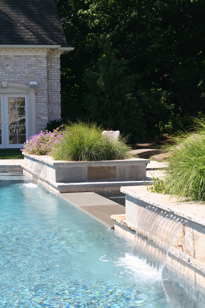 Aménagement d'une piscine classique avec un point d'eau et des pavés en pierre naturelle.