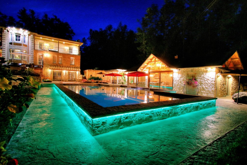 Пример оригинального дизайна: большой прямоугольный бассейн на переднем дворе в средиземноморском стиле с домиком у бассейна и покрытием из декоративного бетона