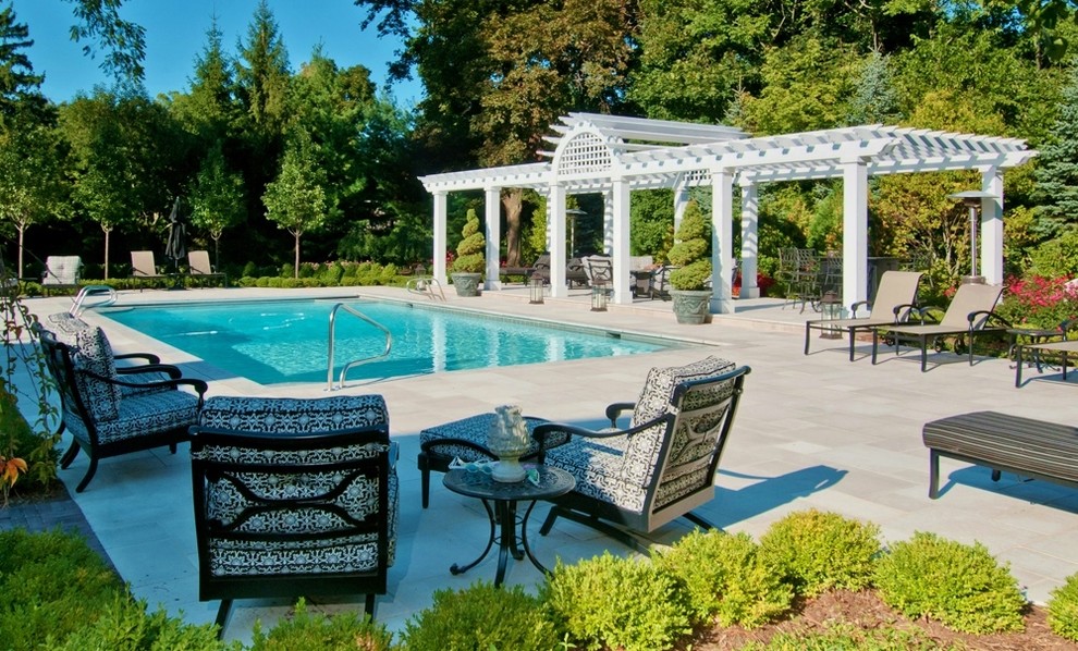 Exempel på en klassisk rektangulär pool på baksidan av huset och insynsskydd, med naturstensplattor