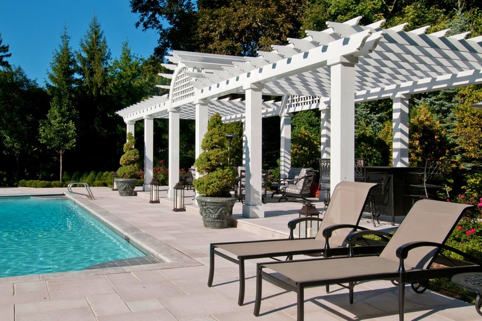 Esempio di una piscina monocorsia chic rettangolare dietro casa con pavimentazioni in pietra naturale e paesaggistica bordo piscina