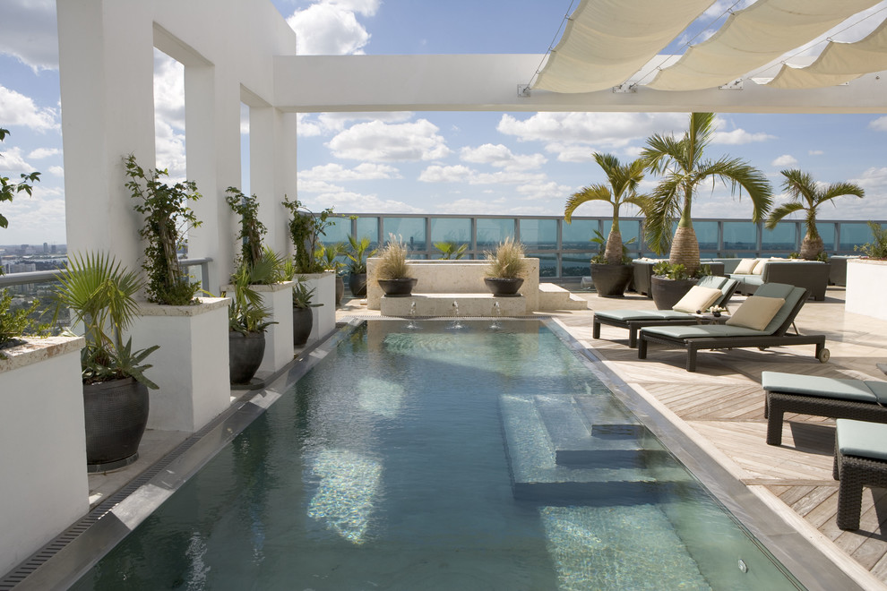 Idee per una grande piscina tropicale rettangolare dietro casa con fontane e pedane