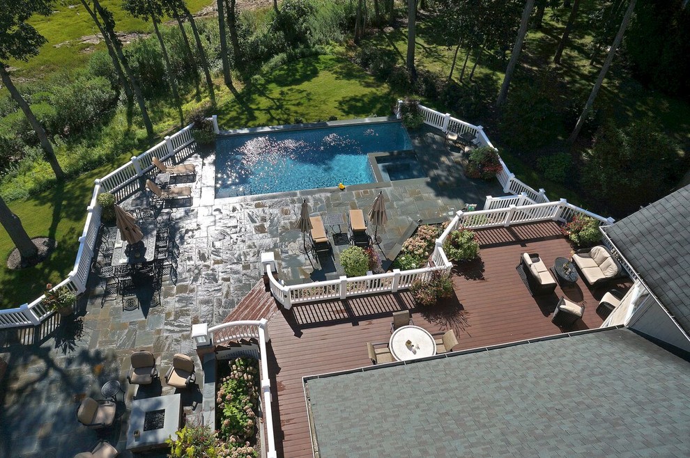 Modelo de piscinas y jacuzzis alargados tradicionales de tamaño medio en forma de L en patio trasero con adoquines de piedra natural