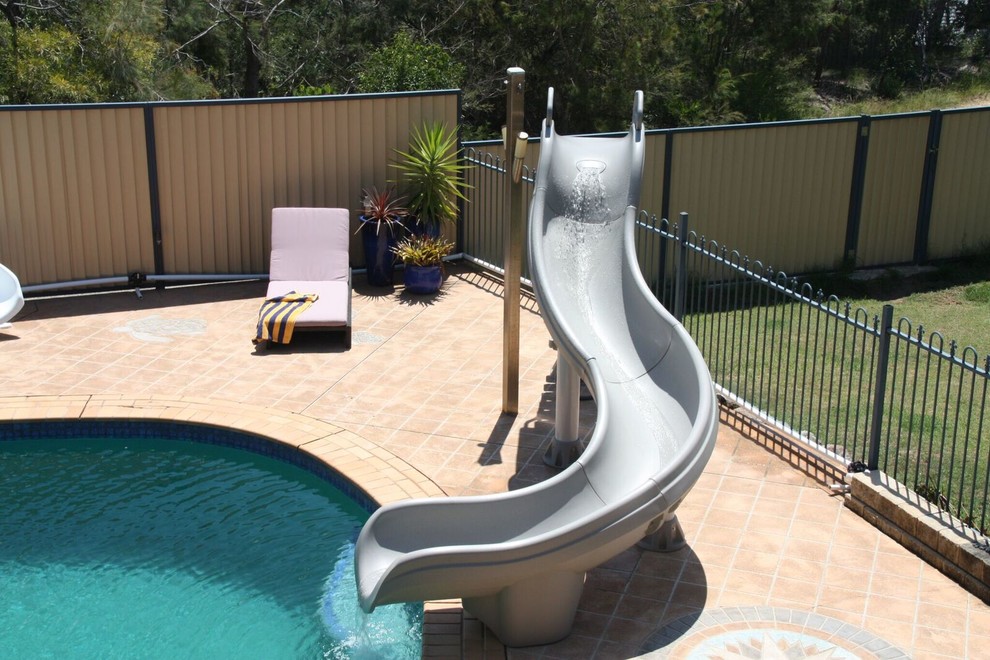 Großer Infinity-Pool hinter dem Haus in individueller Form mit Wasserrutsche und Betonboden in Sydney