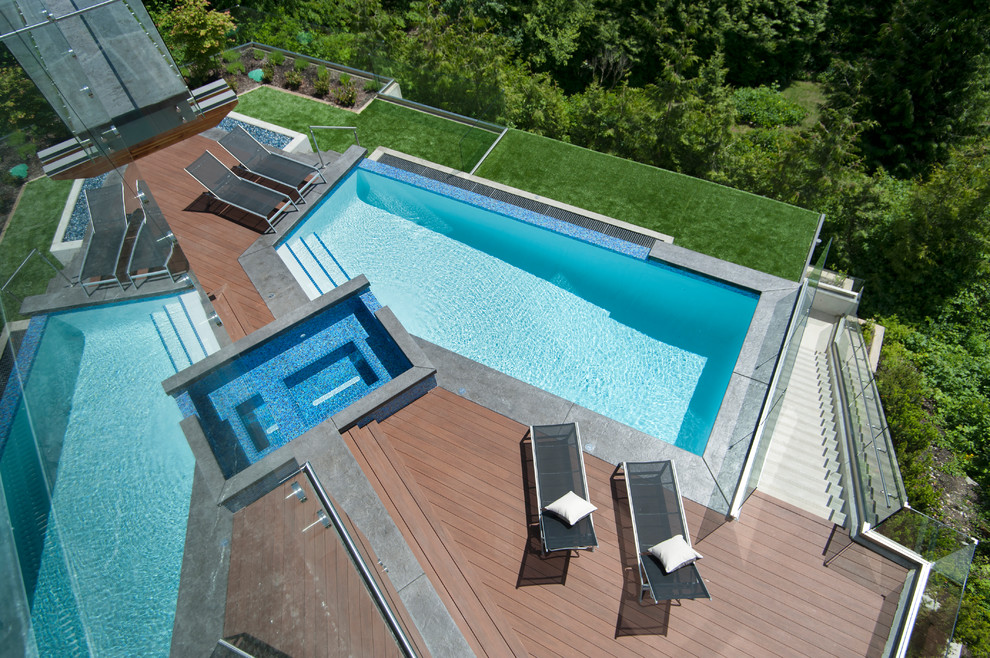 Esempio di una piscina a sfioro infinito minimal personalizzata dietro casa con una vasca idromassaggio e pedane
